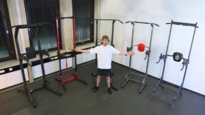 Man in white shirt standing in front of 5 different Power Towers in a gym, including Power Towers by SportsRoyal, ONTWOFIT, RELIFE, Tunturi and Decathlon