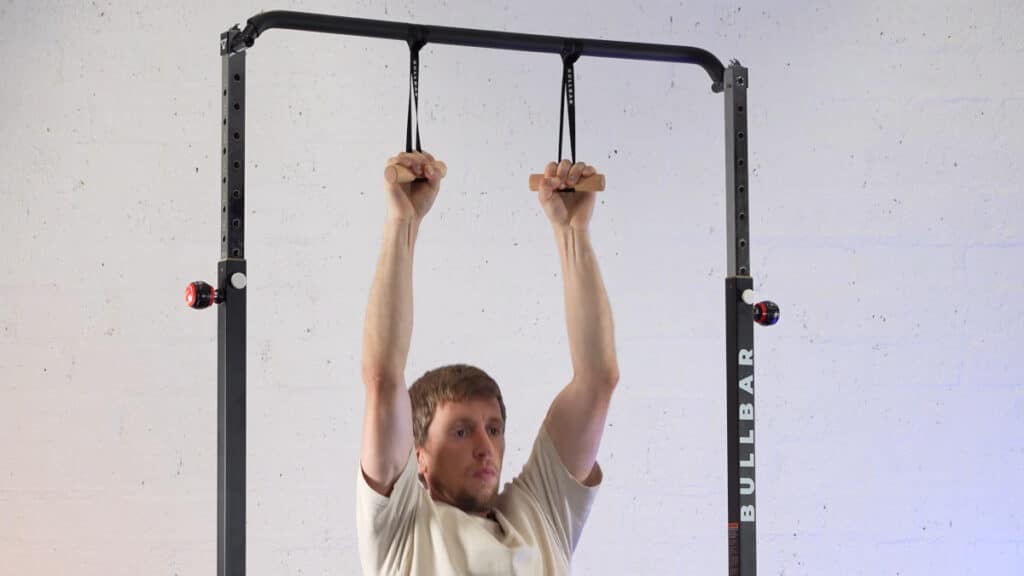Man in white shirt doing pull-ups on a bullbar 2.0 extended pull-up bar using the bullbar pull-up handles.