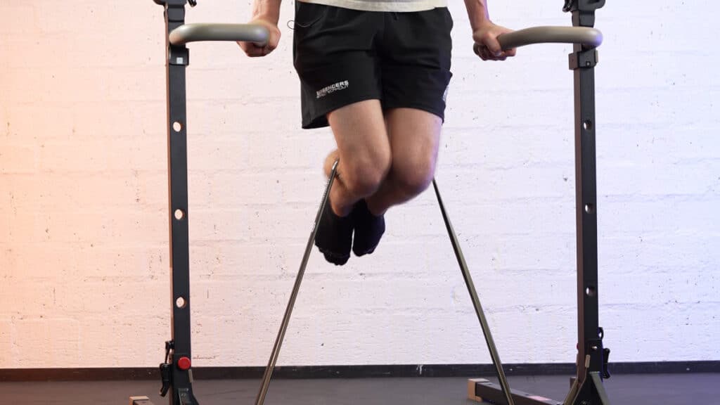 Man doing dips with bullbar resistance bands strapped around his calves to provide additional resistance.