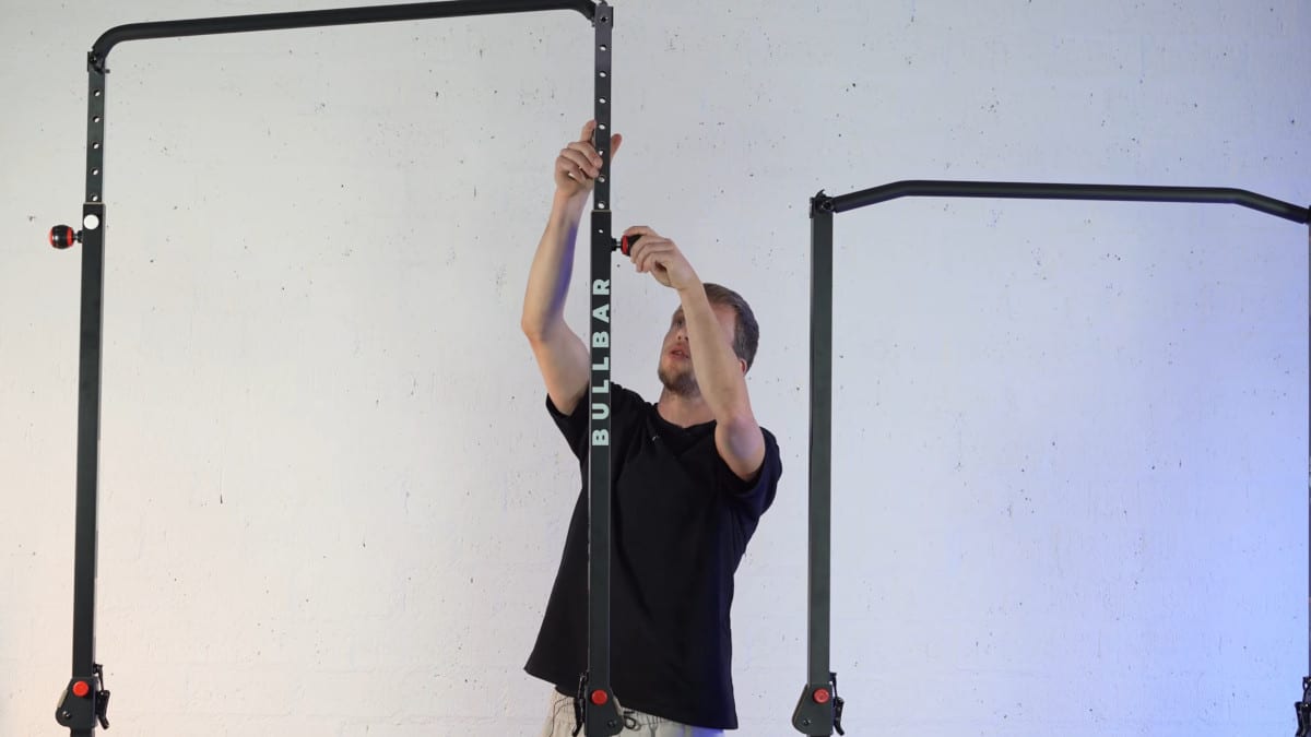 Man in black shirt adjusting the height on the bullbar 2.0 extended by raising one side of the bar before continuing to the other side.