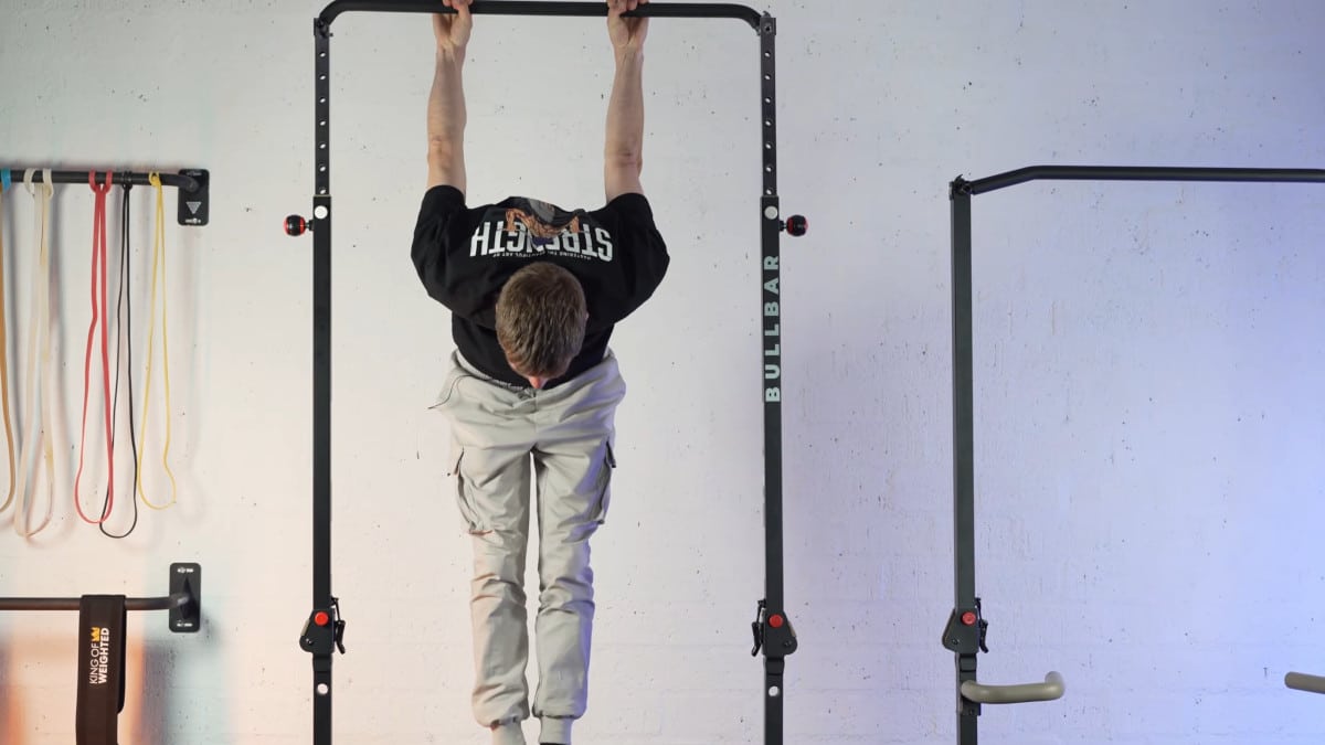 Man in black shirt doing a skin-the-cat on the bullbar 2.0 extended pull-up bar.