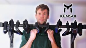 Man hanging from kensui swissies pull-up handles on a pull-up bar, with multiple other kensui swissies also hanging off the same bar and him looking incredulously at the viewer.