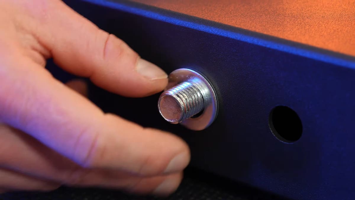 Detail of the king of weighted adjustable dip station, where a man's hand is next to one of the bolts that is used to assemble the product and showing that is nearly as thick as his fingers.