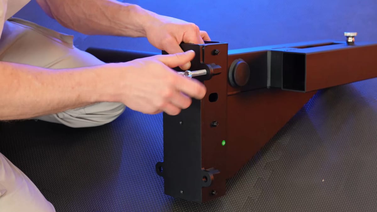 Man assembling the king of weighted adjustable dip station by placing a heavy duty bolt through the rear assembly of the dip bar portion.