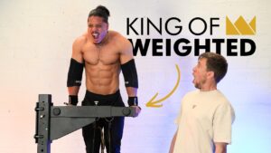 Professional athlete performing dips on the King of Weighted Adjustable Dip Station and visible exerting himself, with another man looking by suprised at the effort.