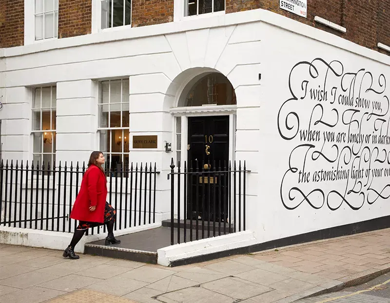 A woman enterting an office building that has writing on the side