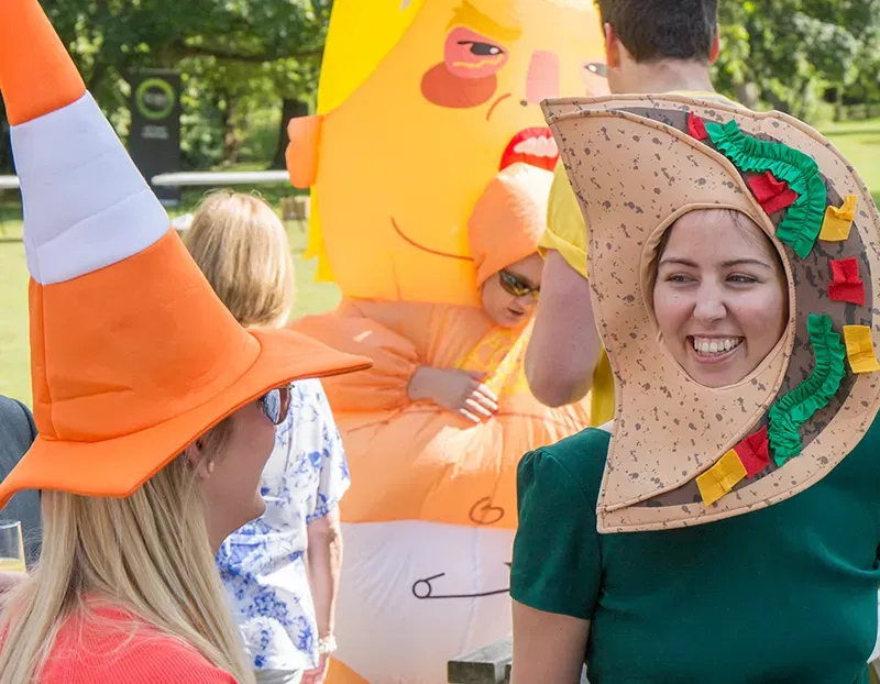 Men and women dressed in fancy dress outfits outdoors at a party
