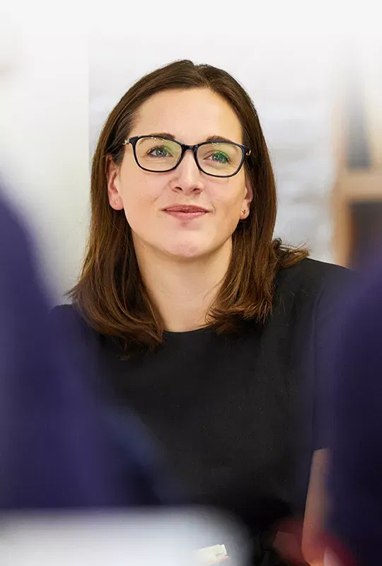 A woman in glasses between two out-of-focus people