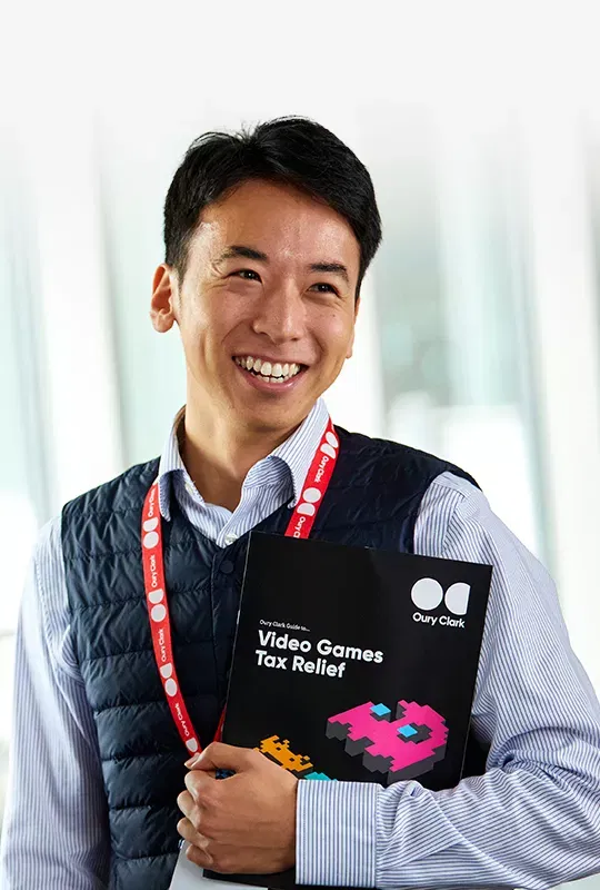 A man holding a copy of an Oury Clark guide to video games tax relief