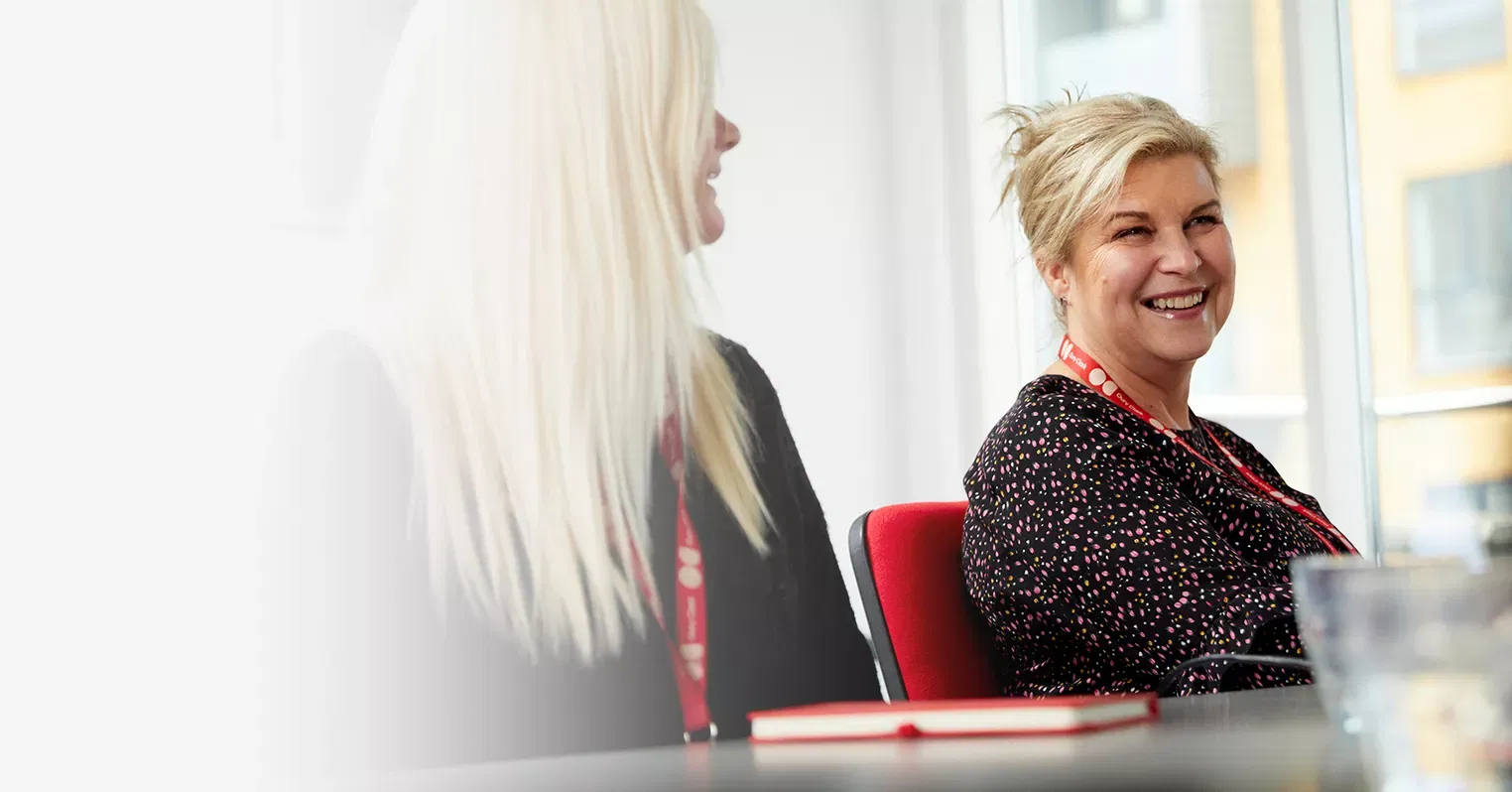 Two smiling women wearing Oury Clark lanyards