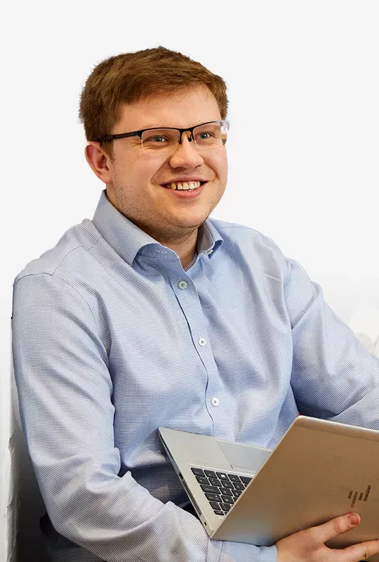 A smiling man in glasses holding a laptop