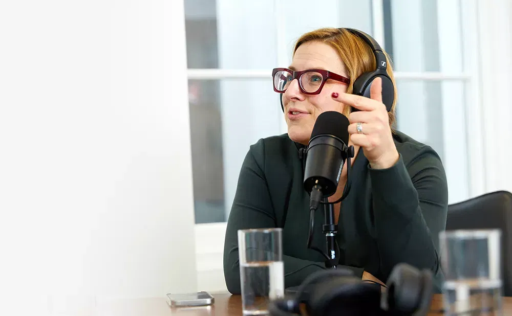 A photo of a woman wearing headphones and talking into a podcast microphone