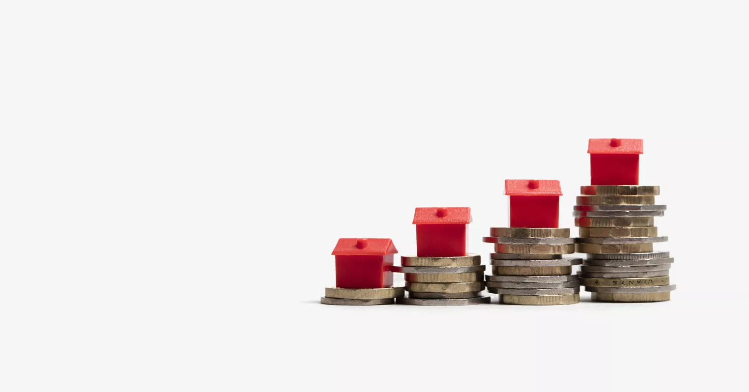 Four different-sized piles of coins, with a red monopoly house on top of each