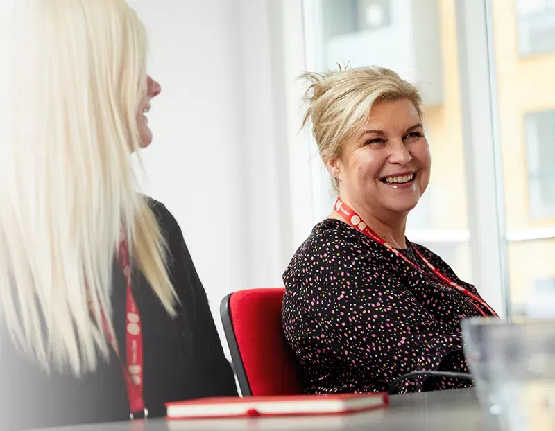 Two smiling women wearing Oury Clark lanyards