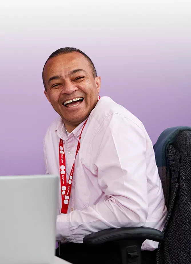 An image of a laughing man in pink shirt wearing an Oury Clark lanyard