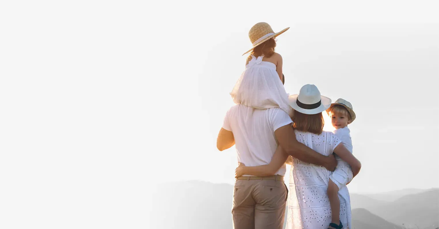 Image of a family of four - a man, a woman and a boy and girl child. The children and the mum are wearing hats, the boy child looking back towards the camera