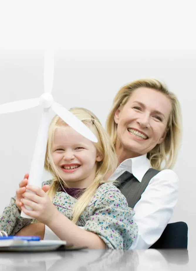 Photo of a woman with a little girl sat on her knee. Both are smiling and the girl is holding a toy