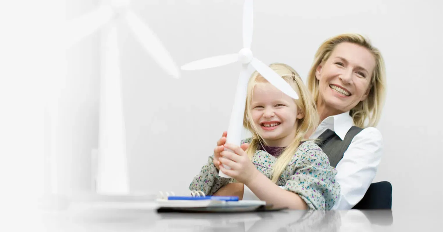 Photo of a woman with a little girl sat on her knee. Both are smiling and the girl is holding a toy