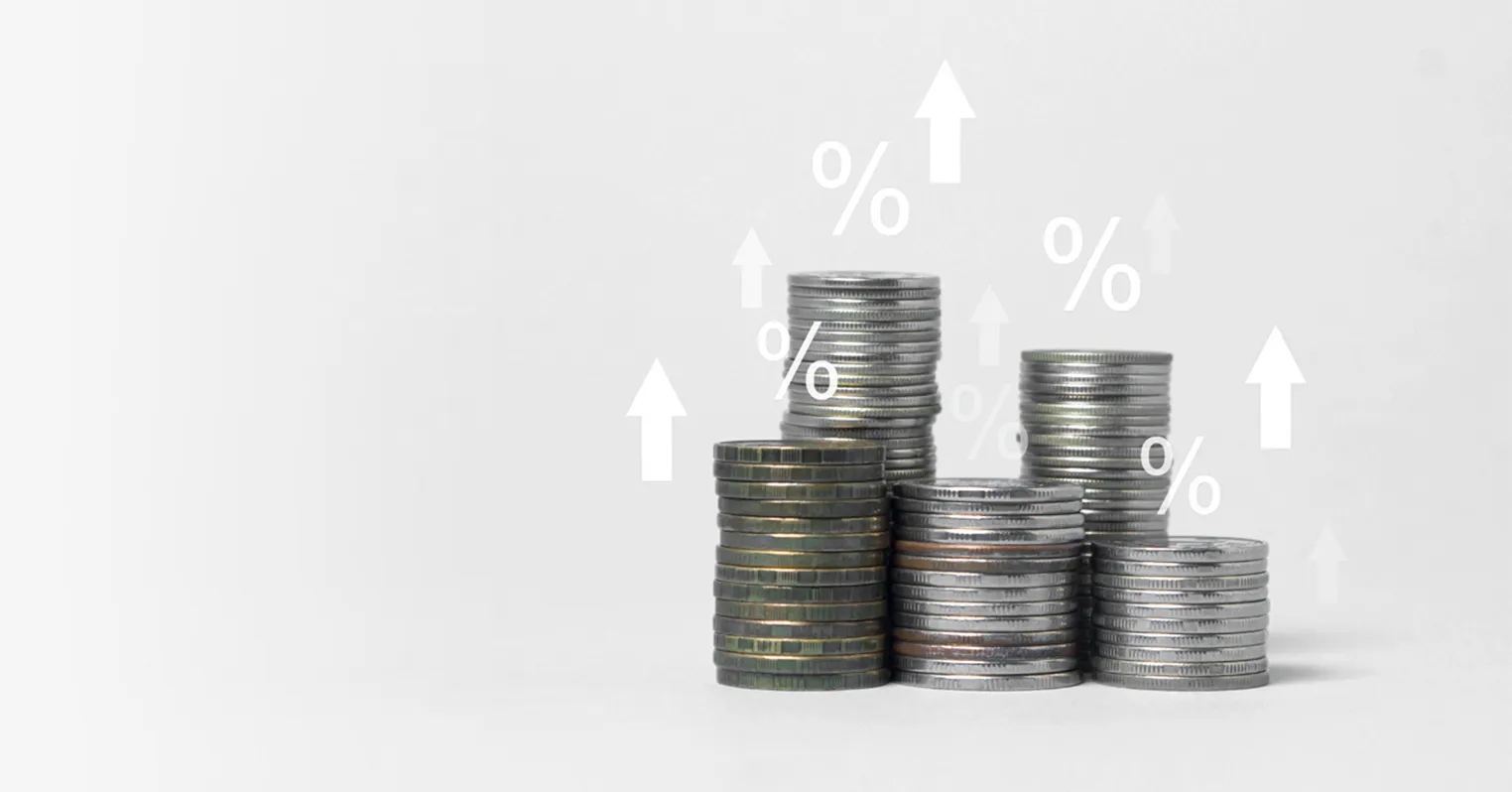 A photo of different stacks of coins, overlaid with arrows pointing upwards and percentage symbols