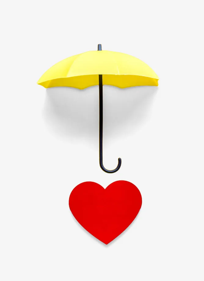 A red paper heart with a yellow umbrella above it