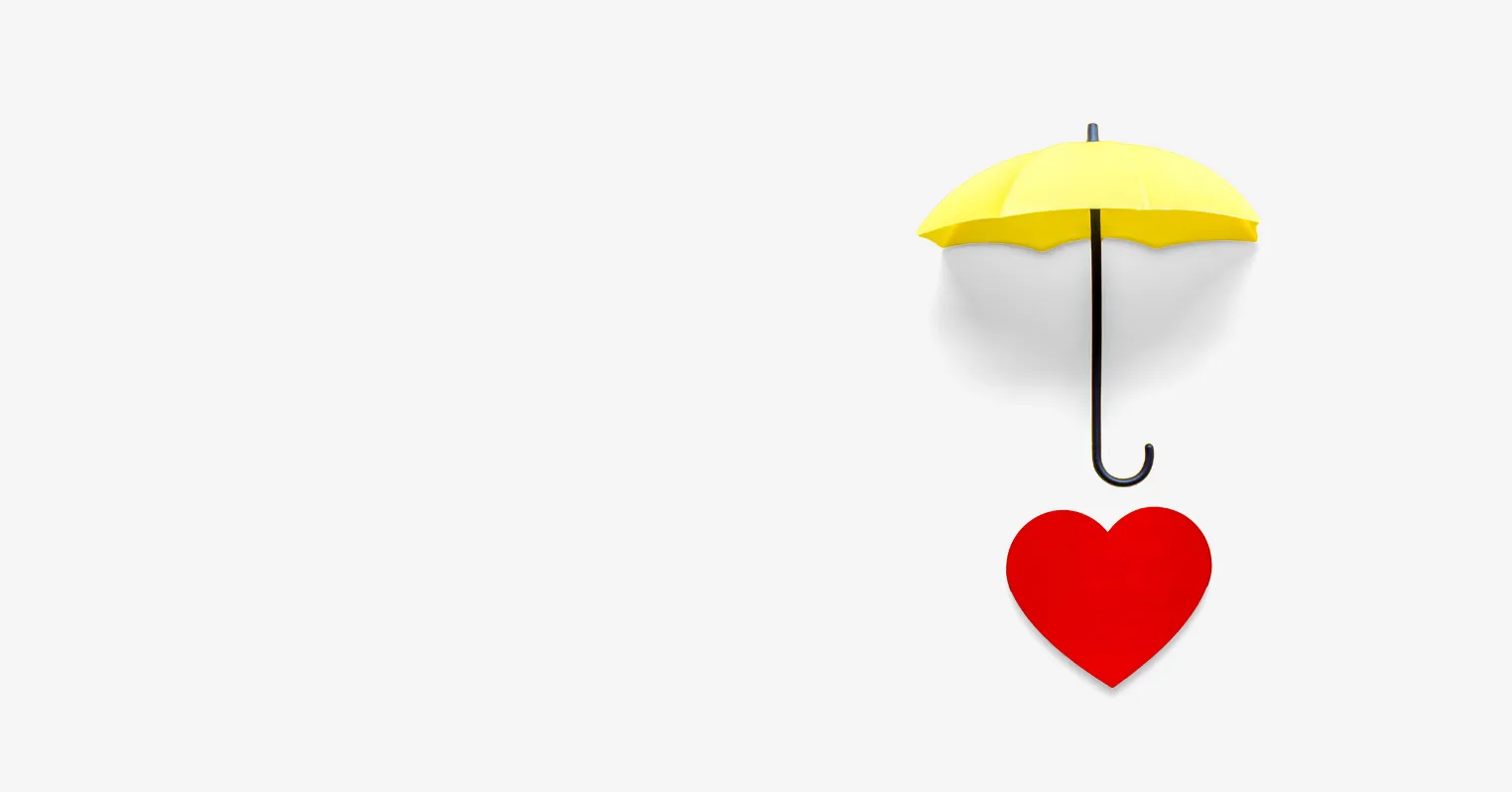 A red paper heart with a yellow umbrella above it