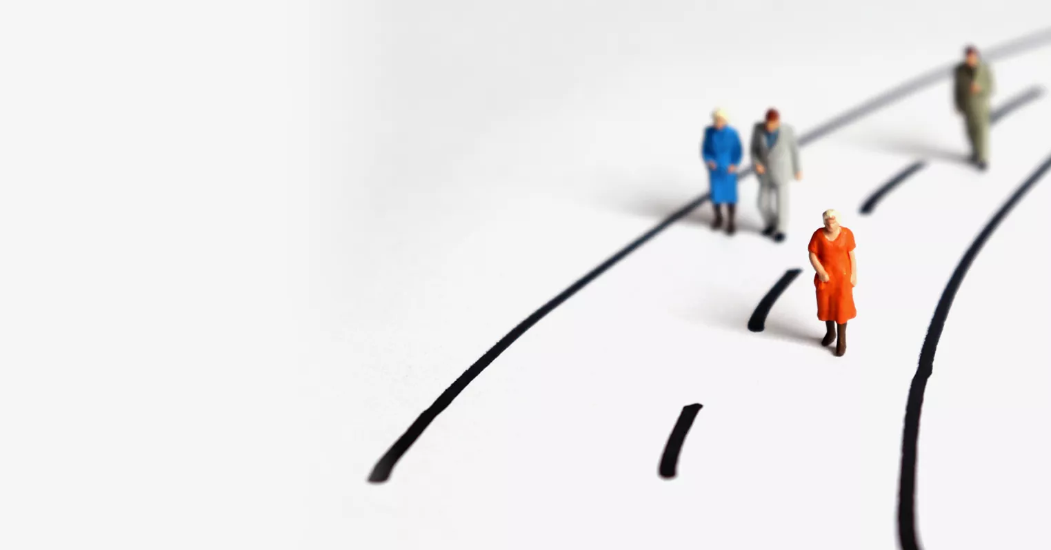 a road drawn onto a white surface with four different toy humans walking along it