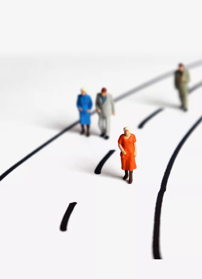 a road drawn onto a white surface with four different toy humans walking along it