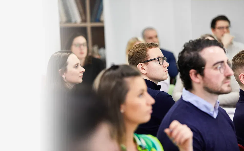 Photo with a blurred left-hand side, then the right side showing a group of people watching something