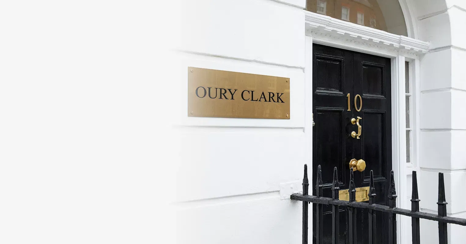 Front door of a house with a number 10 sign on, next to a black railing. On the wall is a gold nameplate with black text reading 'Oury Clark'.