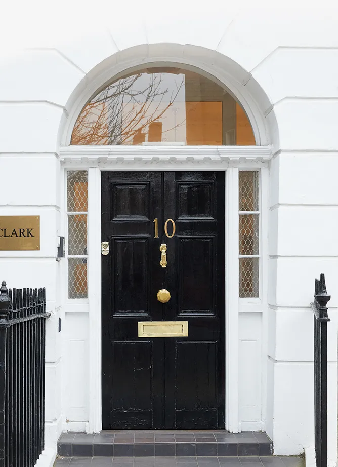 Front door of a house with a number 10 sign on, next to a black railing. On the wall is a gold nameplate with black text reading 'Clark'.