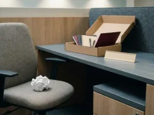 Verfrommeld cv in een lege bureaustoel naast een onaangeroerd onboardingpakket en leeg naambordje op een modern kantoorbureau.